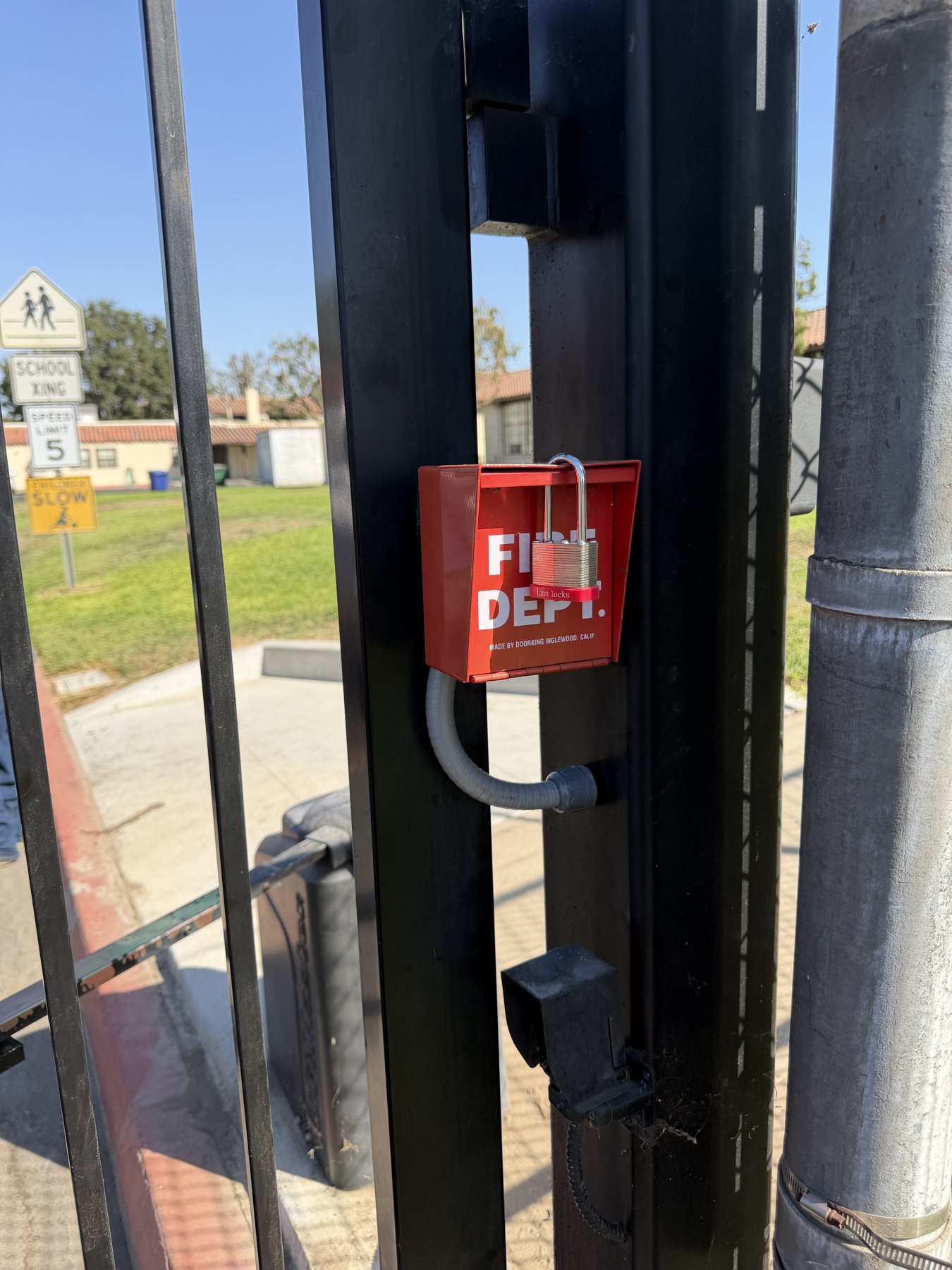 Red fire department access box mounted on the automatic gate at St. LaSalle Elementary School in Reedley, California
